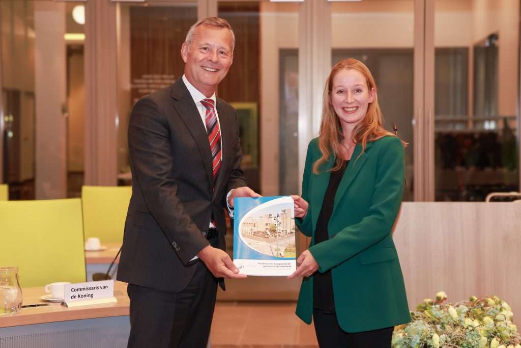 Commissaris van de Koning Arthur van Dijk ontvangt in de raadszaal van de gemeente Drechterland de profielschets voor de nieuwe burgemeester uit handen van Maartje Tros, fractievoorzitter van de Seniorenpartij Drechterland.